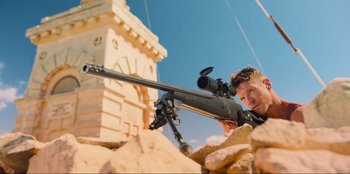 Movie still from “Sniper: G.R.I.T. - Global Response & Intelligence Team” (2023), directed by Oliver Thompson – A man is holding a rifle and aiming it; Wide shot, Low angle