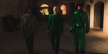 Movie still from “Sniper: G.R.I.T. - Global Response & Intelligence Team” (2023), directed by Oliver Thompson – A group of people walking in a room with stained glass windows in the background; Medium shot, Low angle