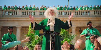 Movie still from “Sniper: G.R.I.T. - Global Response & Intelligence Team” (2023), directed by Oliver Thompson – An old man dressed in a green outfit and white beard; Wide shot, Low angle