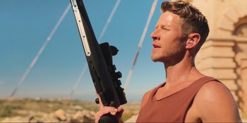 Movie still from “Sniper: G.R.I.T. - Global Response & Intelligence Team” (2023), directed by Oliver Thompson – A man holding a rifle in his hand; Close Up shot, Low angle