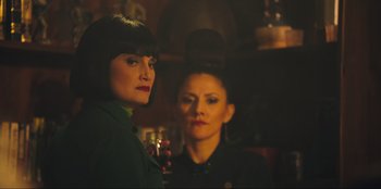 Movie still from “Sniper: G.R.I.T. - Global Response & Intelligence Team” (2023), directed by Oliver Thompson – Two women standing next to each other holding a wine glass; Close Up shot, Over the shoulder angle