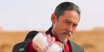 Movie still from “Sniper: G.R.I.T. - Global Response & Intelligence Team” (2023), directed by Oliver Thompson – A person holding something in his hand; Close Up shot, Low angle