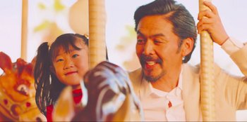 Movie still from “Sniper: G.R.I.T. - Global Response & Intelligence Team” (2023), directed by Oliver Thompson – A man and a little girl riding a carousel; Close Up shot, Over the shoulder angle