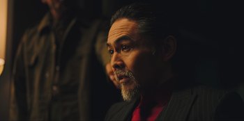 Movie still from “Sniper: G.R.I.T. - Global Response & Intelligence Team” (2023), directed by Oliver Thompson – A person wearing a suit and tie; Close Up shot, Over the shoulder angle