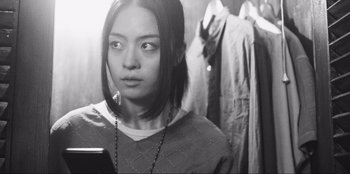 Movie still from “Sniper: G.R.I.T. - Global Response & Intelligence Team” (2023), directed by Oliver Thompson – A young woman looking at the camera while holding a cell phone; Close Up shot, Low angle