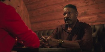 Movie still from “Sniper: G.R.I.T. - Global Response & Intelligence Team” (2023), directed by Oliver Thompson – A man sitting at a table in front of another man; Medium shot, Over the shoulder angle