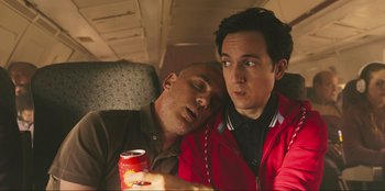 Movie still from “Sniper: G.R.I.T. - Global Response & Intelligence Team” (2023), directed by Oliver Thompson – Two men sleeping next to each other on a couch; Medium shot, Low angle