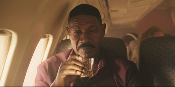 Movie still from “Sniper: G.R.I.T. - Global Response & Intelligence Team” (2023), directed by Oliver Thompson – An older man holding a glass of water; Close Up shot, Low angle