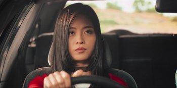 Movie still from “Sniper: G.R.I.T. - Global Response & Intelligence Team” (2023), directed by Oliver Thompson – A woman sitting in the driver's seat of a car; Close Up shot, Low angle