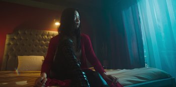 Movie still from “Sniper: G.R.I.T. - Global Response & Intelligence Team” (2023), directed by Oliver Thompson – A woman sitting on top of a bed in a room; Medium shot, Low angle