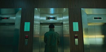 Movie still from “Sniper: G.R.I.T. - Global Response & Intelligence Team” (2023), directed by Oliver Thompson – A man standing in an elevator looking into the lift; Wide shot, Low angle