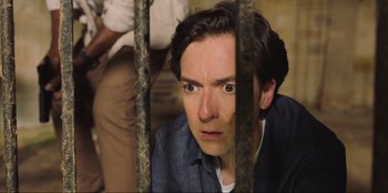 Movie still from “Sniper: G.R.I.T. - Global Response & Intelligence Team” (2023), directed by Oliver Thompson – A man looking through a jail cell bars; Close Up shot, Low angle
