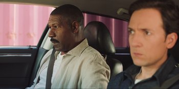 Movie still from “Sniper: G.R.I.T. - Global Response & Intelligence Team” (2023), directed by Oliver Thompson – A man sitting in the back of a car next to another man; Close Up shot, Over the shoulder angle