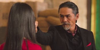 Movie still from “Sniper: G.R.I.T. - Global Response & Intelligence Team” (2023), directed by Oliver Thompson – A man in a black suit and a woman in a red shirt; Close Up shot, Over the shoulder angle