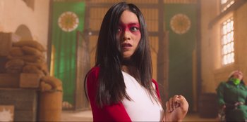 Movie still from “Sniper: G.R.I.T. - Global Response & Intelligence Team” (2023), directed by Oliver Thompson – A woman with long black hair wearing a white and red outfit; Medium shot, Low angle