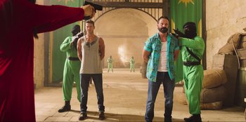 Movie still from “Sniper: G.R.I.T. - Global Response & Intelligence Team” (2023), directed by Oliver Thompson – A group of men standing next to each other in a room; Wide shot, Over the shoulder angle