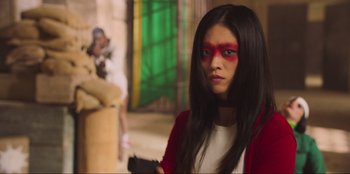 Movie still from “Sniper: G.R.I.T. - Global Response & Intelligence Team” (2023), directed by Oliver Thompson – A young woman with red and black makeup on her face; Medium shot, Over the shoulder angle