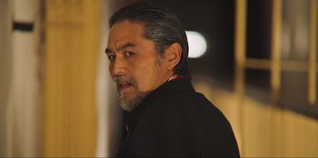 Movie still from “Sniper: G.R.I.T. - Global Response & Intelligence Team” (2023), directed by Oliver Thompson – A person wearing a black shirt; Close Up shot, Low angle