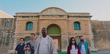 Movie still from “Sniper: G.R.I.T. - Global Response & Intelligence Team” (2023), directed by Oliver Thompson – A group of people standing in front of a building; Wide shot, Low angle
