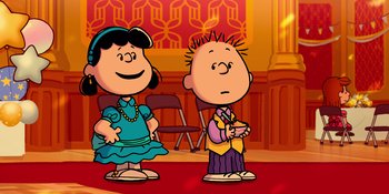 Movie still from “Snoopy Presents: For Auld Lang Syne” (2021), directed by Clay Kaytis – A couple of people standing next to each other on a stage; Medium shot, High angle