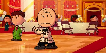 Movie still from “Snoopy Presents: For Auld Lang Syne” (2021), directed by Clay Kaytis – A charlie brown cartoon character in front of an empty chair; Extreme Wide shot, High angle