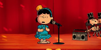 Movie still from “Snoopy Presents: For Auld Lang Syne” (2021), directed by Clay Kaytis – A cartoon of a girl singing into a microphone on a stage; Medium shot, High angle