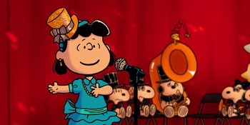 Movie still from “Snoopy Presents: For Auld Lang Syne” (2021), directed by Clay Kaytis – A group of peanuts characters sitting in front of a microphone; Extreme Wide shot, High angle