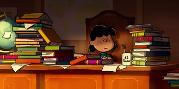 Movie still from “Snoopy Presents: Lucy's School” (2022), directed by Raymond S. Persi – A girl sitting at a desk with a stack of books; Extreme Wide shot, High angle