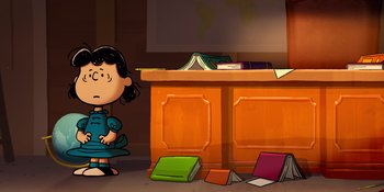 Movie still from “Snoopy Presents: Lucy's School” (2022), directed by Raymond S. Persi – A girl standing in front of a desk with books; Wide shot, High angle