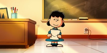 Movie still from “Snoopy Presents: Lucy's School” (2022), directed by Raymond S. Persi – A girl is holding a piece of paper in front of a chalkboard; Medium shot, Low angle