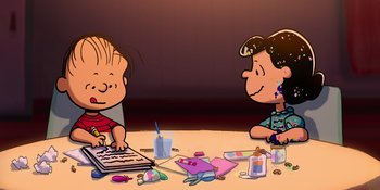 Movie still from “Snoopy Presents: To Mom (and Dad), with Love” (2022), directed by Clay Kaytis – A couple of people sitting at a table with a laptop; Medium shot, High angle