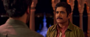 A man with a mustache is talking to another man