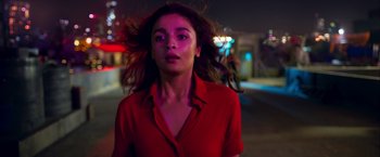 A woman in a red shirt standing on a street