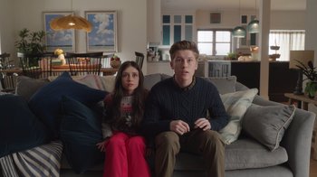Movie still from “Snow Day” (2022), directed by Michael Lembeck – A man and a woman sitting on a couch; Medium shot, Low angle