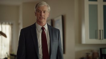 Movie still from “Snow Day” (2022), directed by Michael Lembeck – A man in a suit and tie standing in front of a mirror; Medium shot, Over the shoulder angle