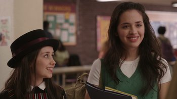 Movie still from “Snow Day” (2022), directed by Michael Lembeck – Two young women smiling for the camera in a classroom setting; Close Up shot, Over the shoulder angle