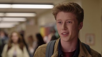Movie still from “Snow Day” (2022), directed by Michael Lembeck – A young man with a backpack is smiling for the camera; Close Up shot, Over the shoulder angle
