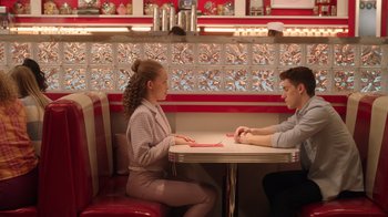 Movie still from “Snow Day” (2022), directed by Michael Lembeck – A woman and a man sitting at a table in a restaurant; Medium shot, High angle