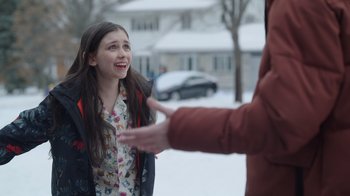 Movie still from “Snow Day” (2022), directed by Michael Lembeck – A young girl is smiling and talking to a person; Medium shot, Over the shoulder angle