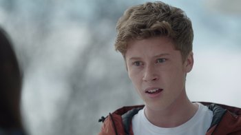 Movie still from “Snow Day” (2022), directed by Michael Lembeck – A person wearing a jacket with trees in the background; Close Up shot, Over the shoulder angle
