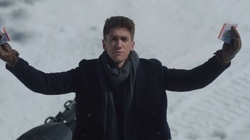 Movie still from “Snow Day” (2022), directed by Michael Lembeck – A man in a black jacket and a scarf; Medium shot, Low angle