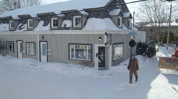 Movie still from “Snow Day” (2022), directed by Michael Lembeck – A person walking in the snow in front of a building; Extreme Wide shot, High angle