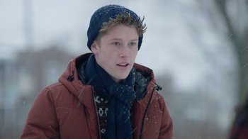 Movie still from “Snow Day” (2022), directed by Michael Lembeck – A young man wearing a red jacket and a blue hat; Close Up shot, Over the shoulder angle