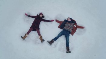 Movie still from “Snow Day” (2022), directed by Michael Lembeck – Two people laying in the middle of the snow making snow angels; Wide shot, Overhead angle