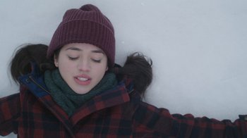 Movie still from “Snow Day” (2022), directed by Michael Lembeck – A woman laying in the snow with her eyes closed; Close Up shot, Overhead angle