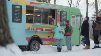 Movie still from “Snow Day” (2022), directed by Michael Lembeck – Two people standing in front of a colorful food truck; Wide shot, Low angle