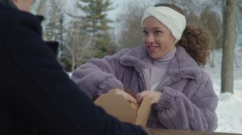 Movie still from “Snow Day” (2022), directed by Michael Lembeck – A woman sitting at a table holding a box; Close Up shot, Over the shoulder angle