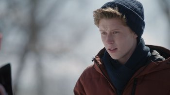 Movie still from “Snow Day” (2022), directed by Michael Lembeck – A young man wearing a red jacket and a blue hat; Close Up shot, High angle