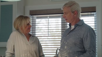 Movie still from “Snow Day” (2022), directed by Michael Lembeck – An older man and a younger woman standing next to each other in front of a window; Medium shot, Over the shoulder angle