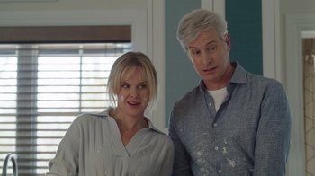 Movie still from “Snow Day” (2022), directed by Michael Lembeck – A man and a woman standing next to each other in a room; Medium shot, Over the shoulder angle
